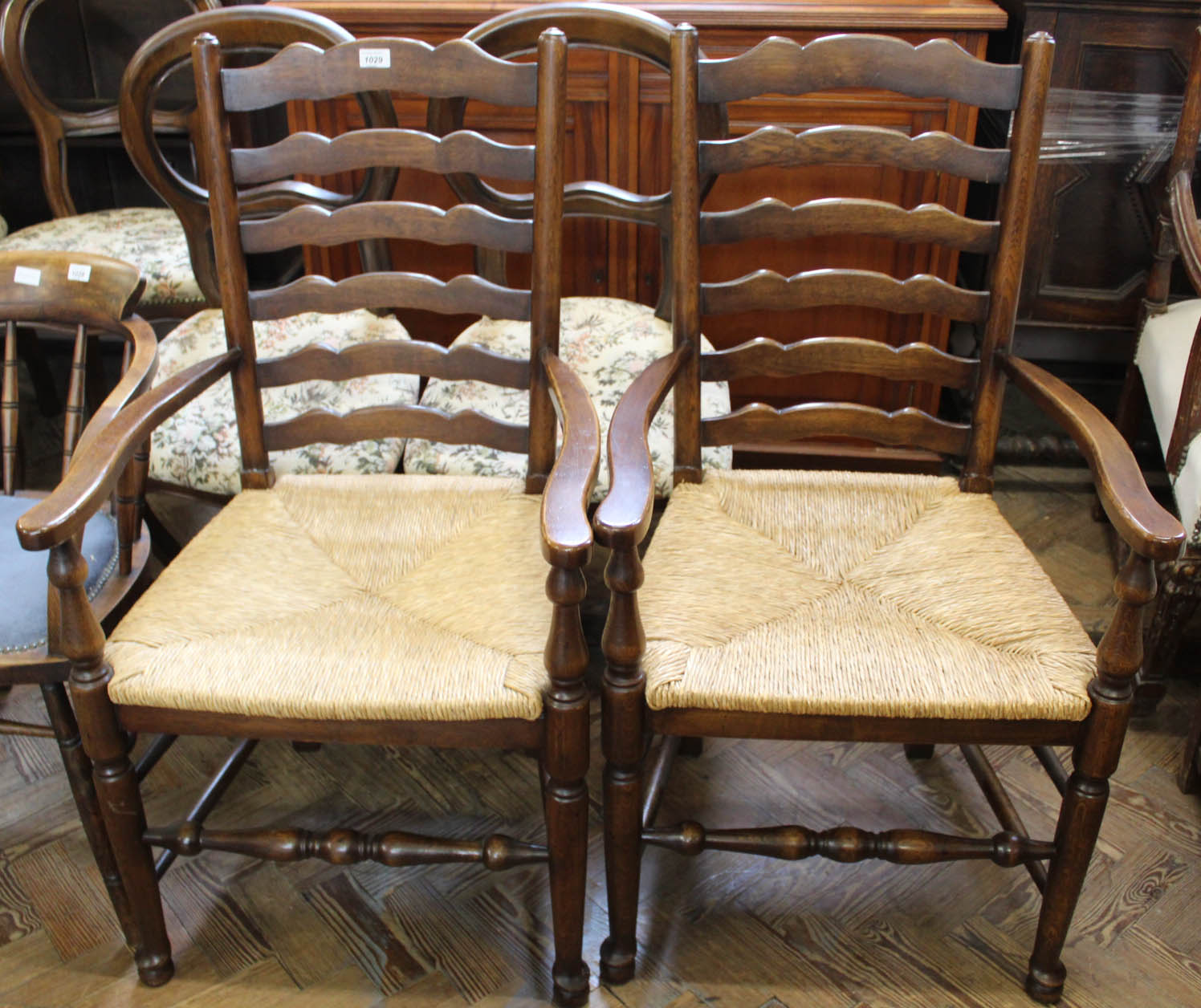 A pair of oak rush seated ladder back carvers