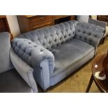 A two seater blue velvet chesterfield style sofa