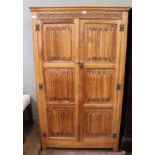 A carved light oak linen fold two door wardrobe