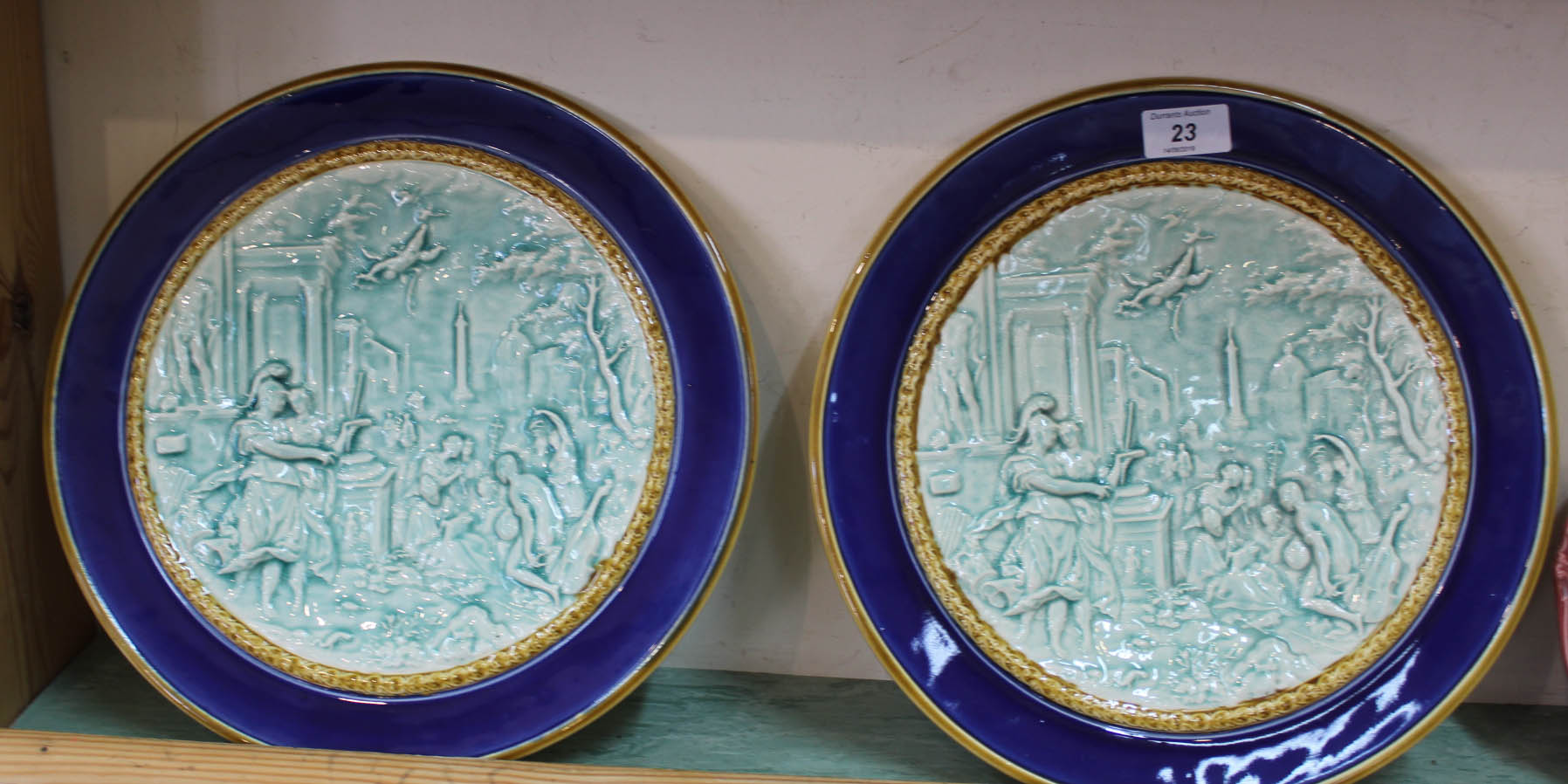 A pair of French pottery wall plates with relief classical scene decoration