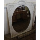 A reproduction white painted and gilt oval mirror in a square frame