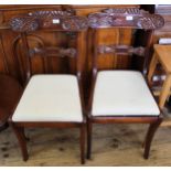 A pair of Victorian carved mahogany dining chairs with cream seats