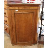 A late Georgian oak hanging corner cupboard