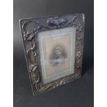 A large Art Nouveau silver photograph frame with embossed floral decoration (slight loss to one