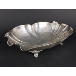 A large white metal bowl with shaped edges on four scroll feet,