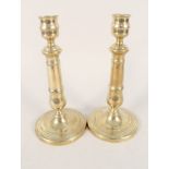 A pair of early 19th Century French brass candlesticks with engraved decoration on circular bases,