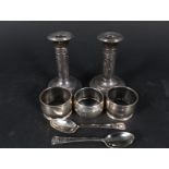 A pair of silver candlesticks (as found), three silver napkin rings,