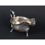 A silver gravy boat with ribbed border on three hoof feet