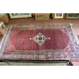 A Persian red ground floral rug,