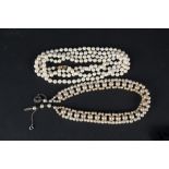 An opera length cultured pearl necklace with 9ct gold stone set clasp plus a faux pearl choker with