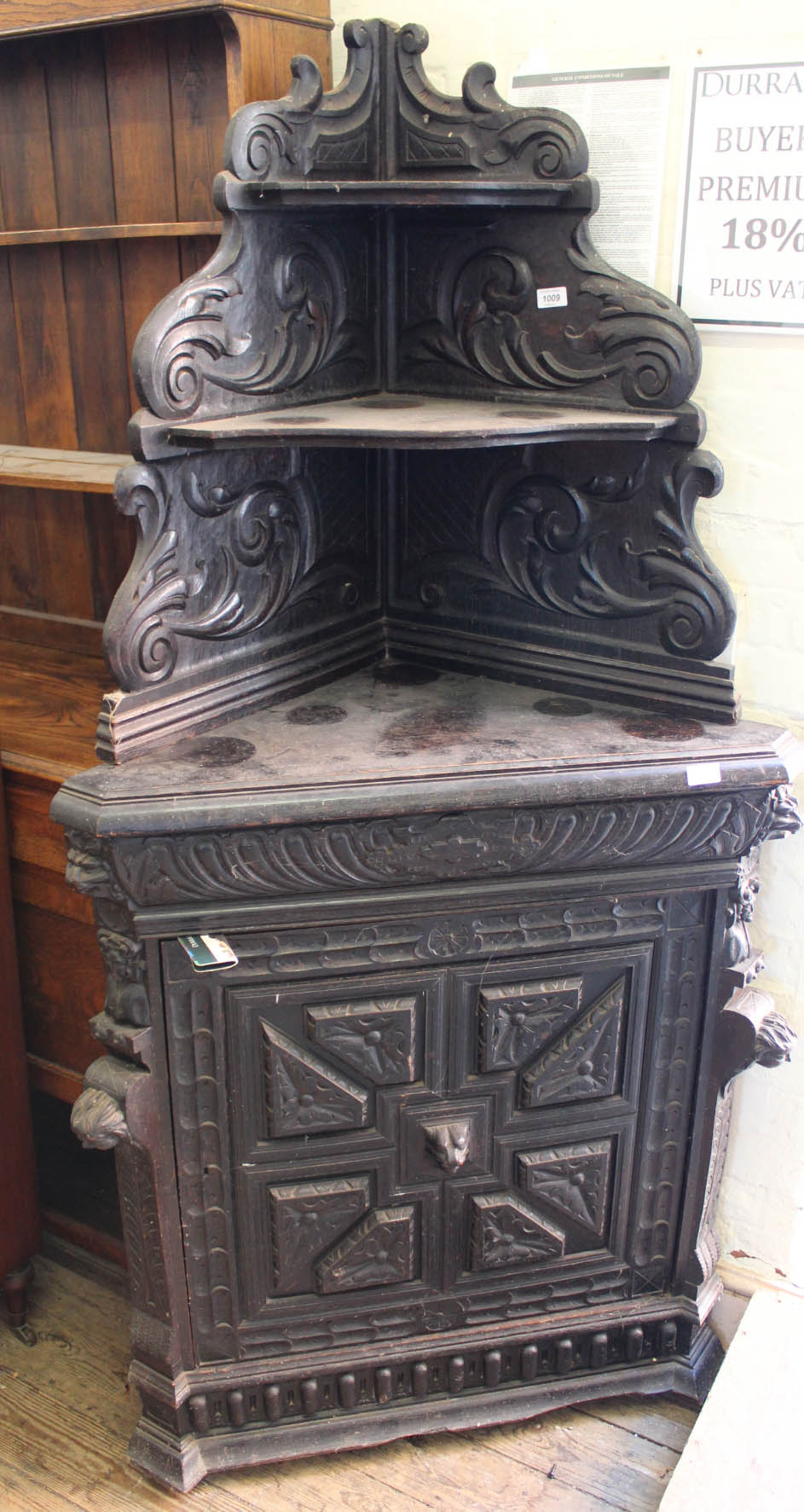 A heavily carved ebonised corner cupboard with two tier upstand