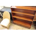A Lloyd Loom gold chair and a reproduction bookcase with two drawers on castors