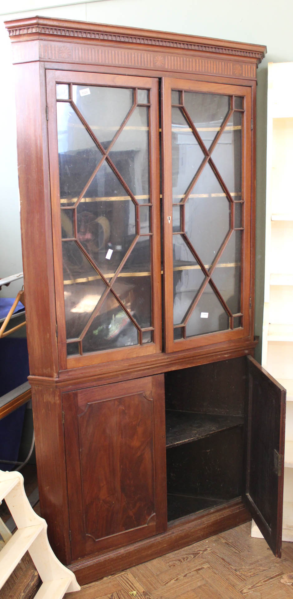 A Georgian mahogany two part corner cabinet with astragal glazed upper door and painted interior on