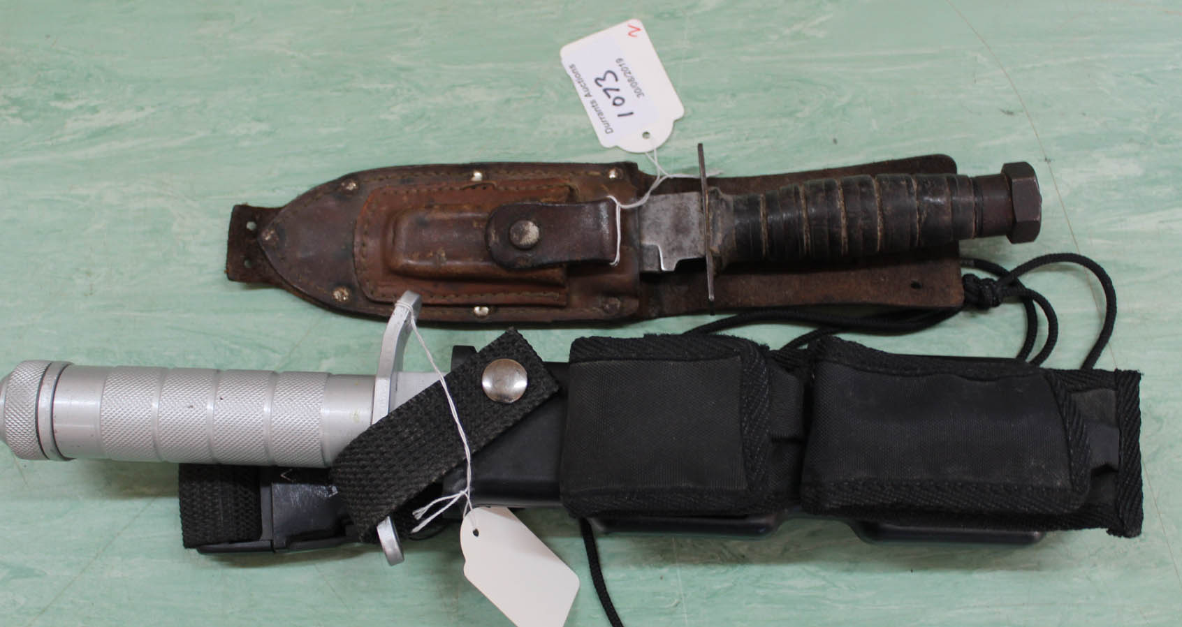 A modern stainless steel survival knife with sheath and accessories with a vintage sheath knife