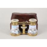 A cased pair of 19th Century brass and mother of pearl opera glasses with painted enamel figure and