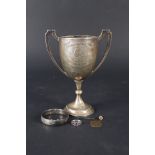 A silver two handled trophy cup (as found), a silver bracelet,