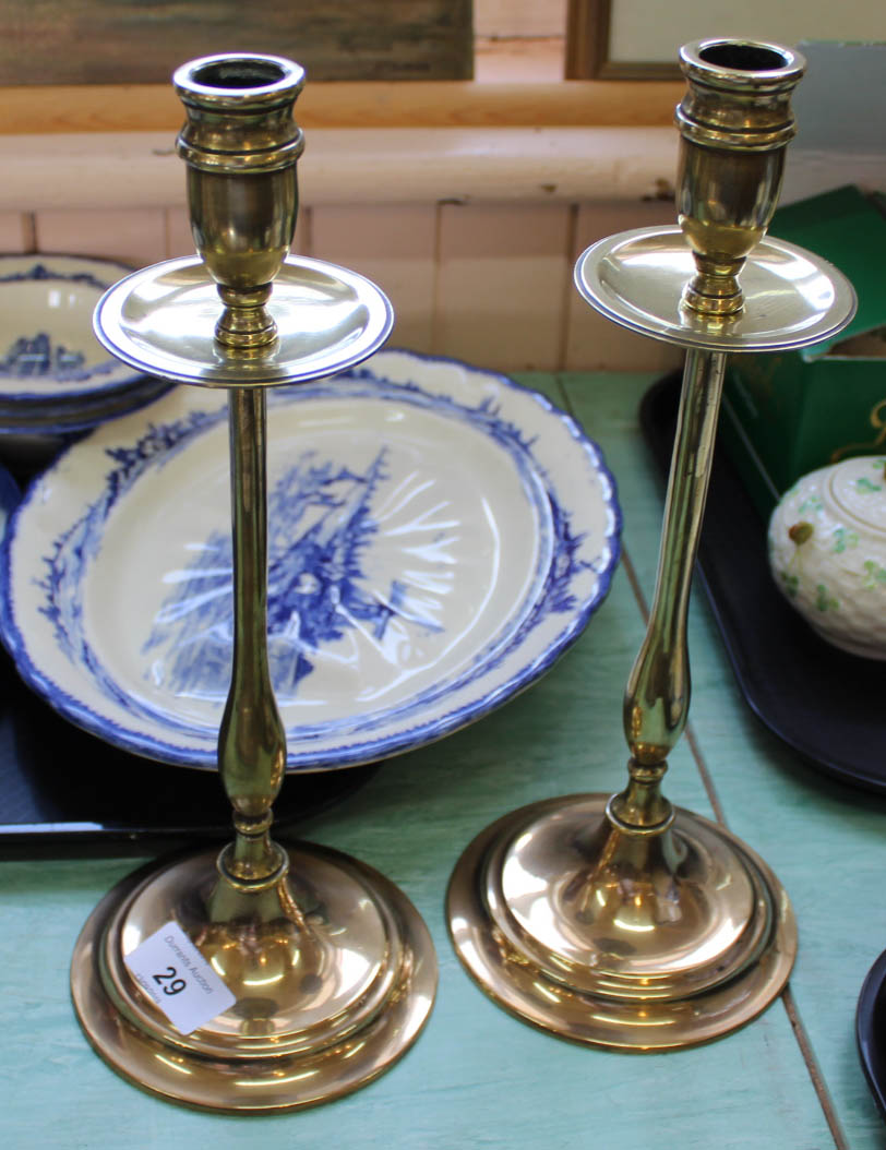 A pair of Edwardian brass candlesticks with drip trays, slender stems and circular bases,