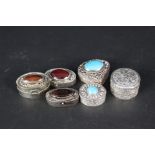 Six white metal pill pots, five set with various stones to lid, all with engraved decoration,
