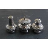 An oriental white metal three piece set cruet decorated with flora,