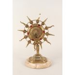 A brass zodiac sunburst clock with cabochon red stones on variegated marble base