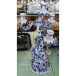 A 19th Century Sitzendorf three branch blue and white candelabra with seated lady and rose