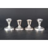 Two pairs of squat silver candlesticks