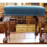 A Victorian carved mahogany foot stool with ball and claw feet