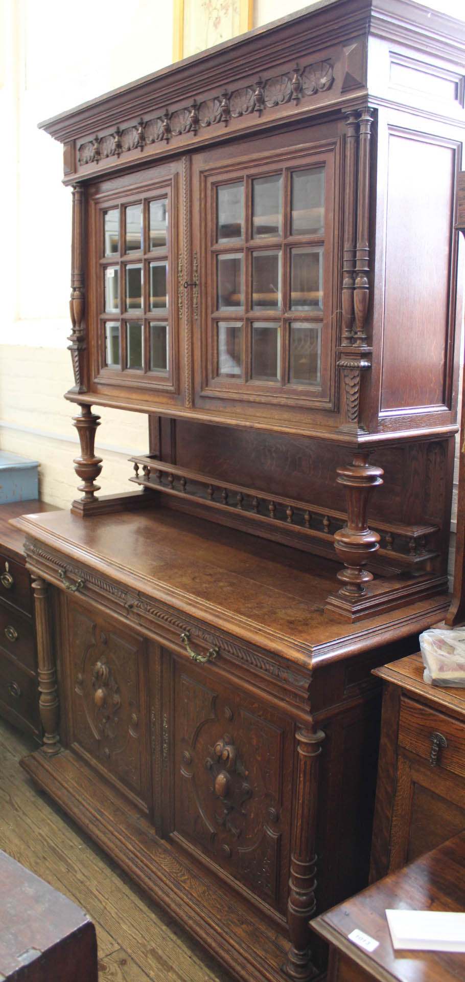 A 1920's carved oak two part glazed cupboard with bevelled glass