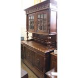 A 1920's carved oak two part glazed cupboard with bevelled glass