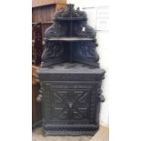 A heavily carved ebonised corner cupboard with two tier upstand