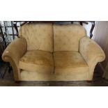 A modern two seater sofa in sandy coloured upholstery