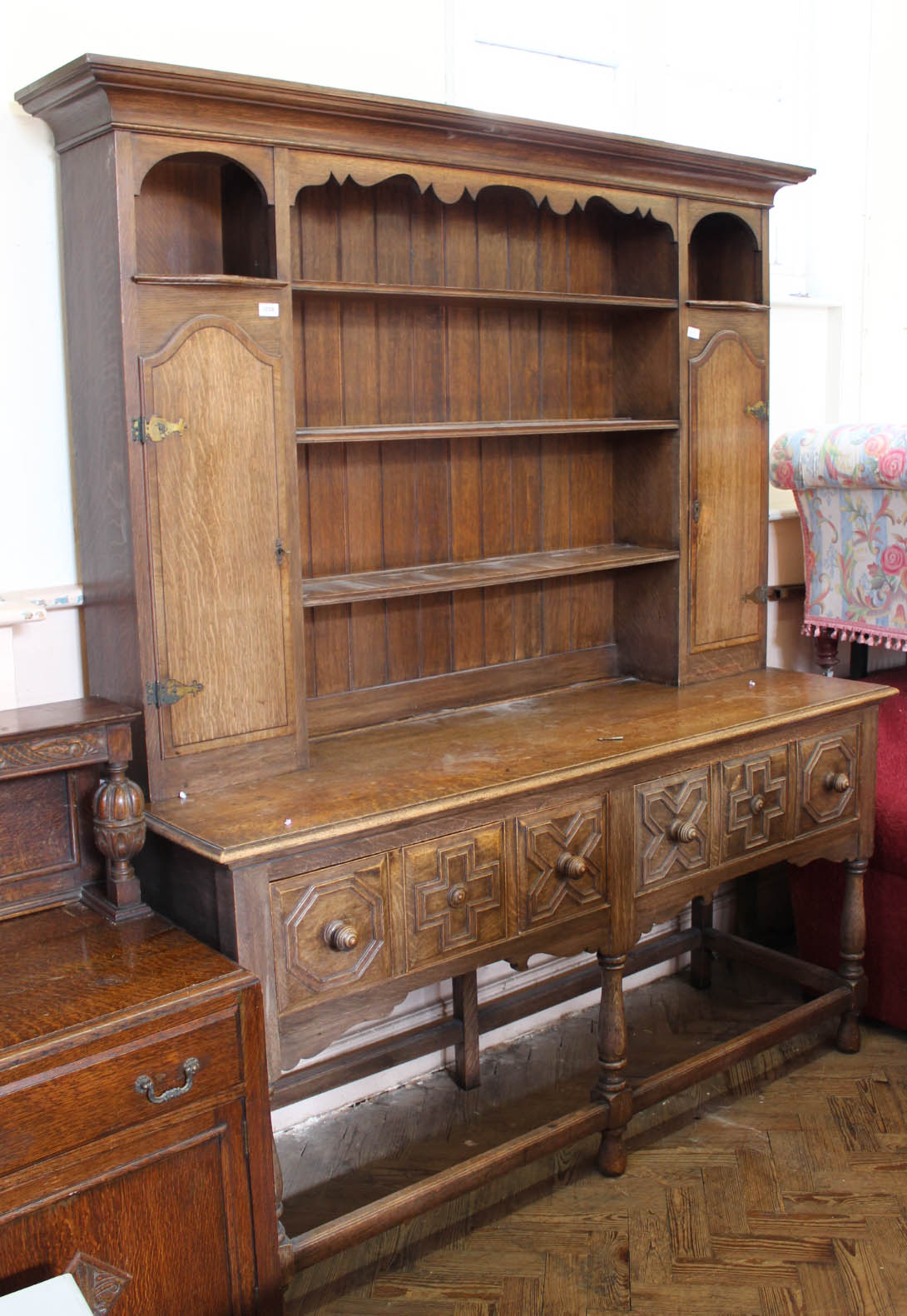 A 1940's oak dresser with moulded drawers on stretcher base and two door top with open shelved