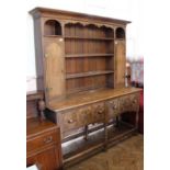 A 1940's oak dresser with moulded drawers on stretcher base and two door top with open shelved