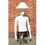 An unusual lamp made from a male shop mannequin on a metal stand