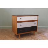 A wooden chest of three drawers on splayed legs with black and white painted drawers and black