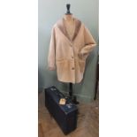 A lady's sheepskin coat by Nurseys of Bungay and a blue suitcase