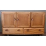 An Ercol Windsor style elm sideboard, with three cupboard doors and two drawers below,