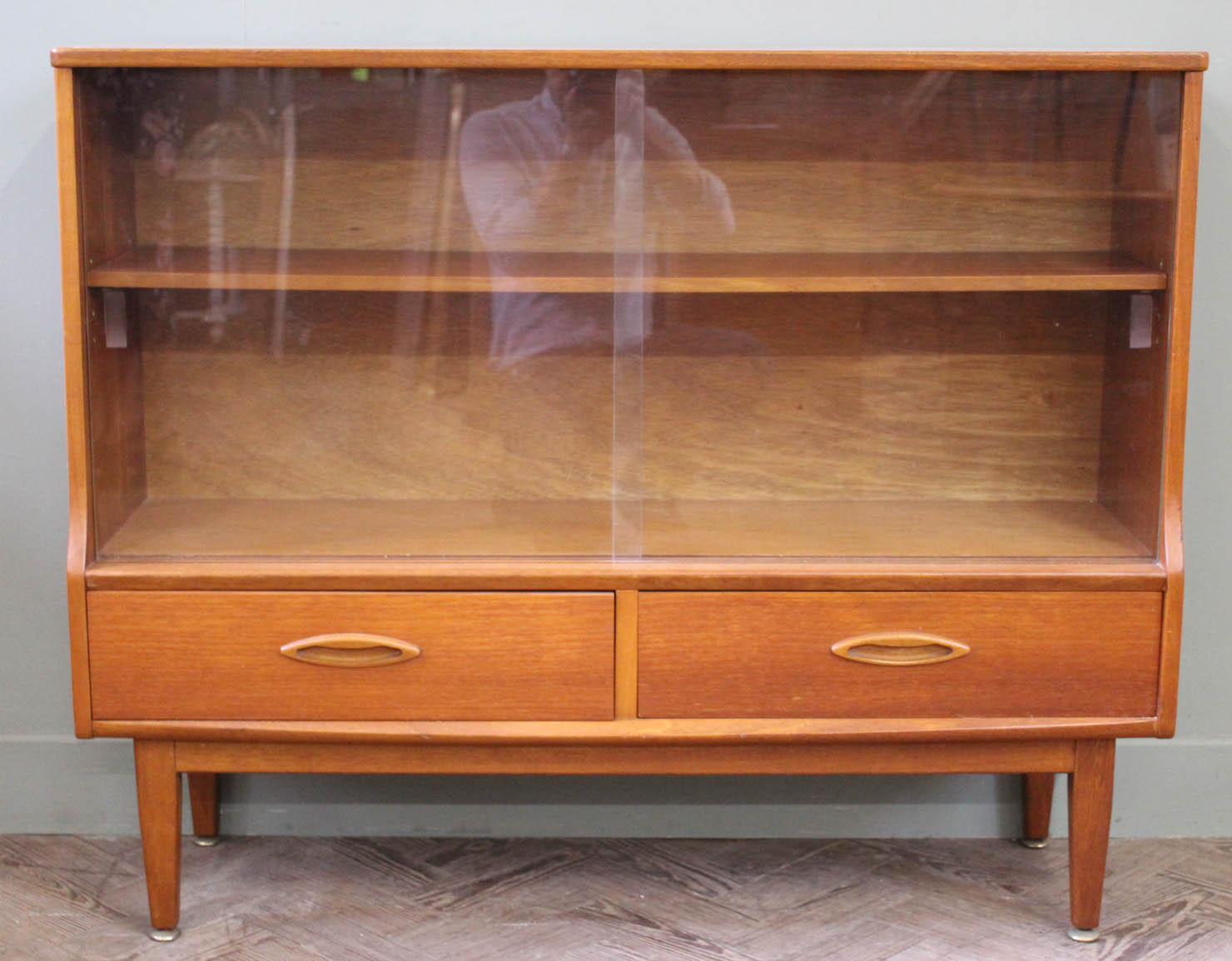 A 1970's glazed teak bookcase on tapered legs with two drawers