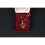 A 9ct gold heart shaped pendant with pierced decoration and garnets set to centre on 9ct gold box