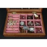 A silver charm bracelet hung with various charms plus a selection of costume jewellery in a wooden,