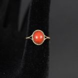 A 9ct gold ring set with oval coral stone with rope border,