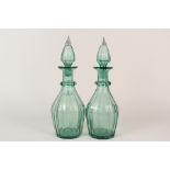 A pair of 19th Century green tinted glass panel cut decanters with silver tipped stoppers