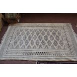 A Persian style cream ground machine made rug with repeating central medallions,