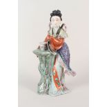 A Chinese polychrome porcelain figurine of a lady with a flower vase,