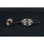 A silver shell shaped sifter spoon together with a silver strainer