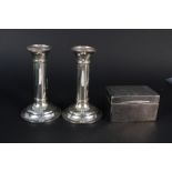 A pair of silver candlesticks (heavily dented) and a small silver cigarette box (as found)