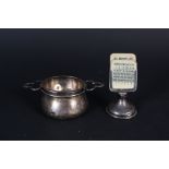 A silver tea strainer and bowl together with a small silver desk calendar, loaded base,