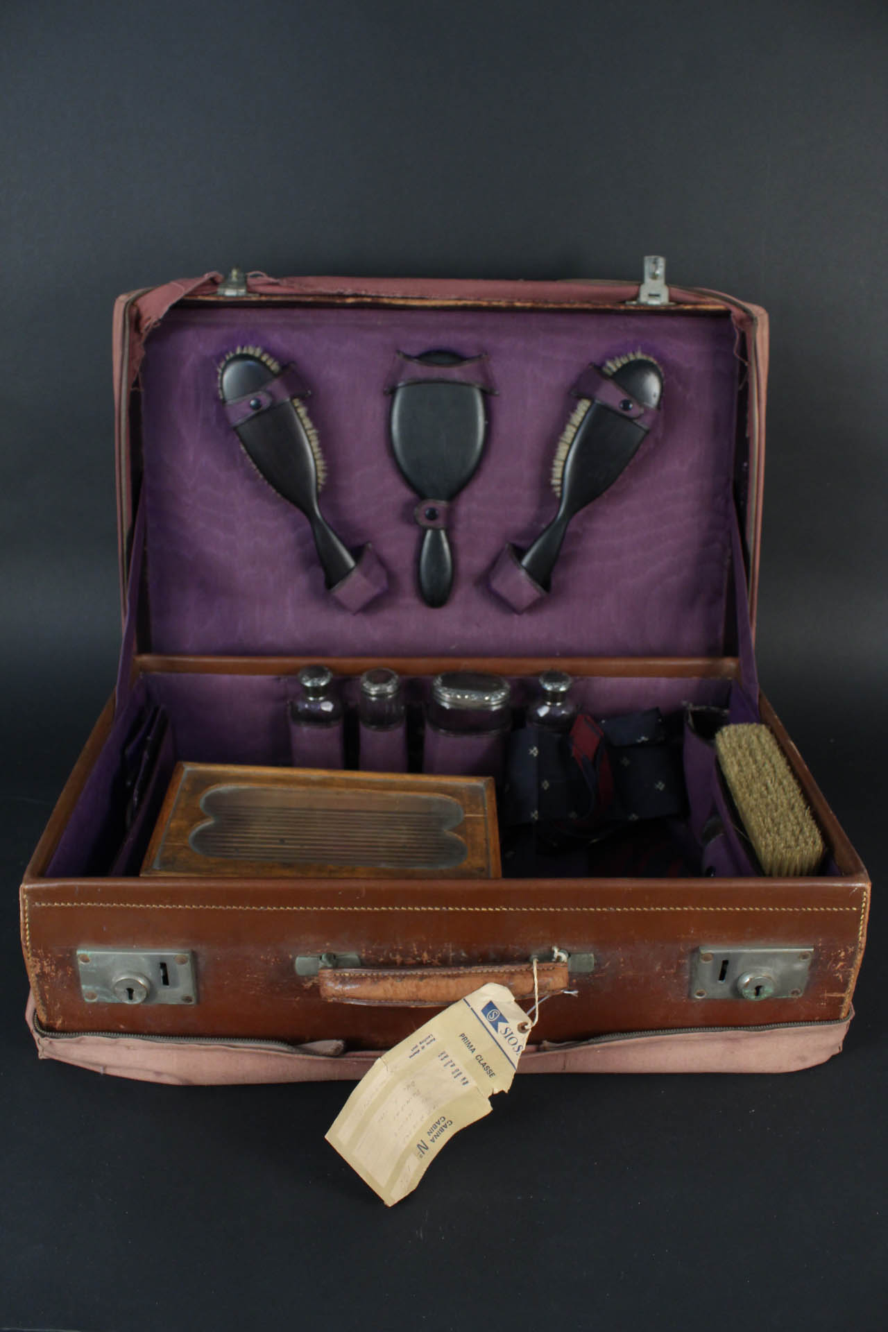 A leather travelling case with contents including ebony brushes,