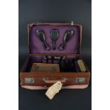 A leather travelling case with contents including ebony brushes,