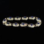 A gold bracelet consisting of oval links set with sapphires and small diamonds,
